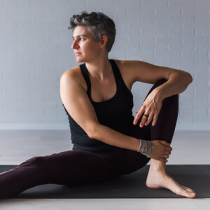 Mature Caucasian woman practicing yoga on livingroom floor. Midd